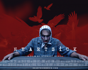 A man wearing make up and a headscarf grips a table, a red and black background with shadowed birds fly behind him
